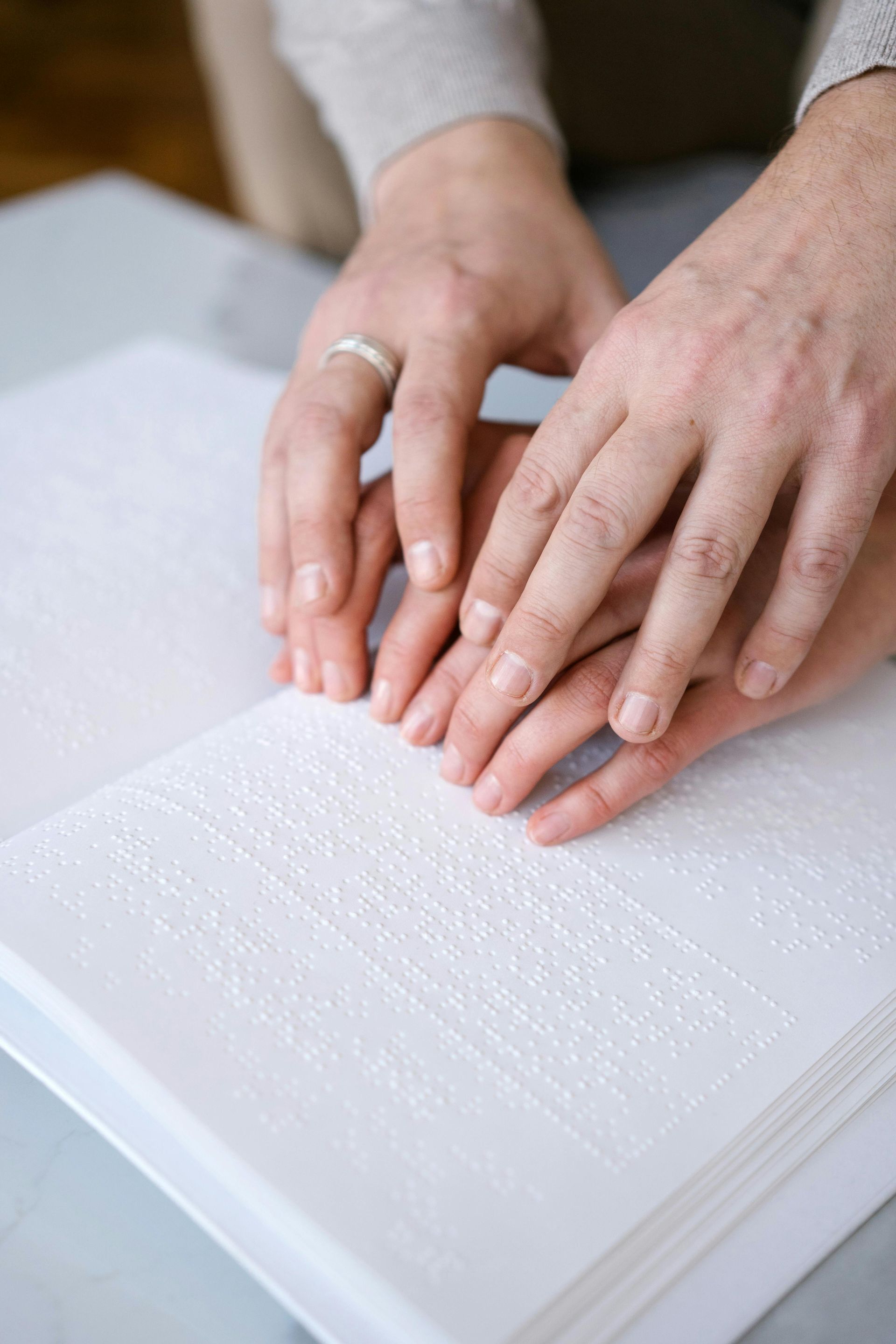 Hands placing a ring on an open white textured book
