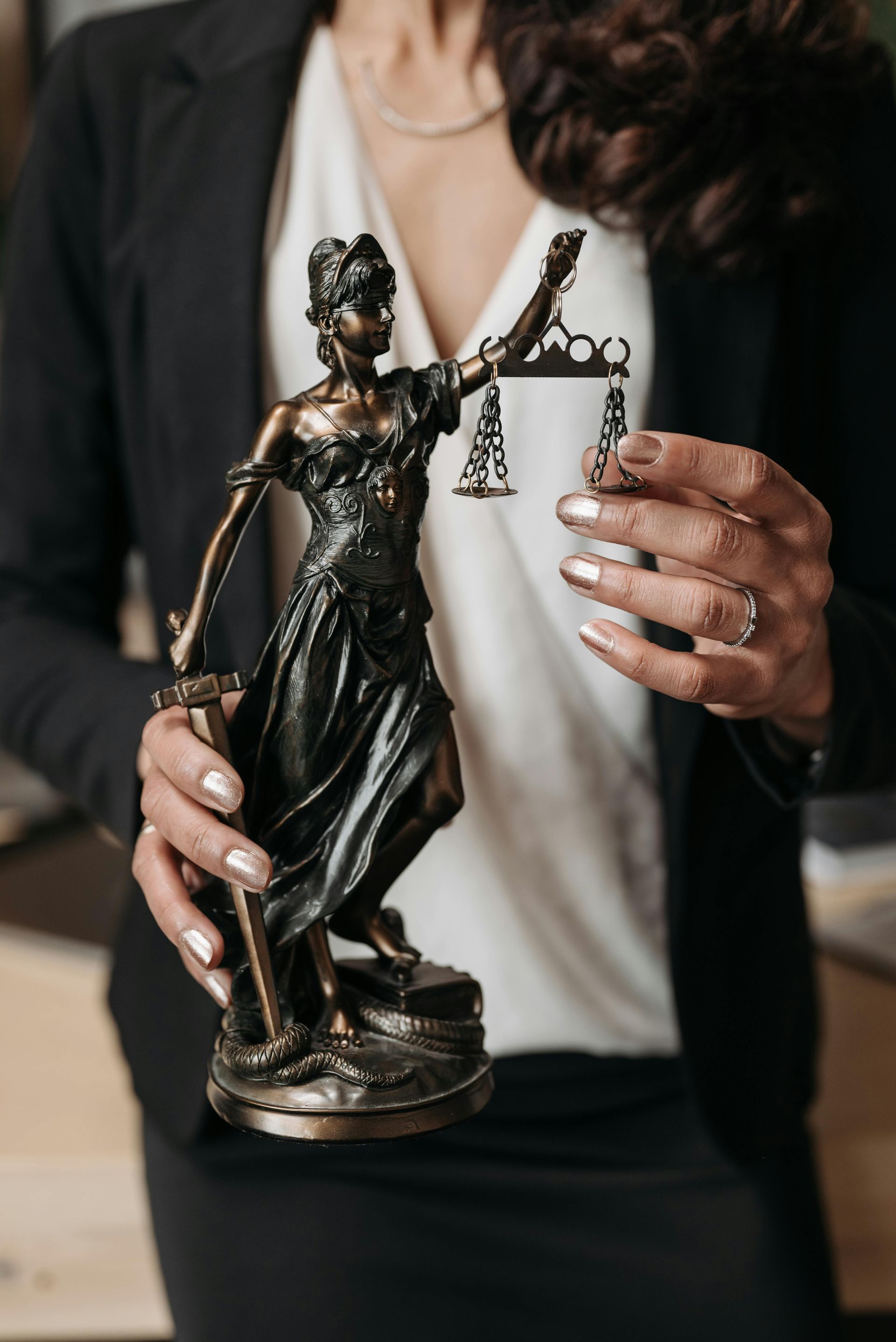 Hands holding a dark statuette trophy and a champagne glass at a formal event