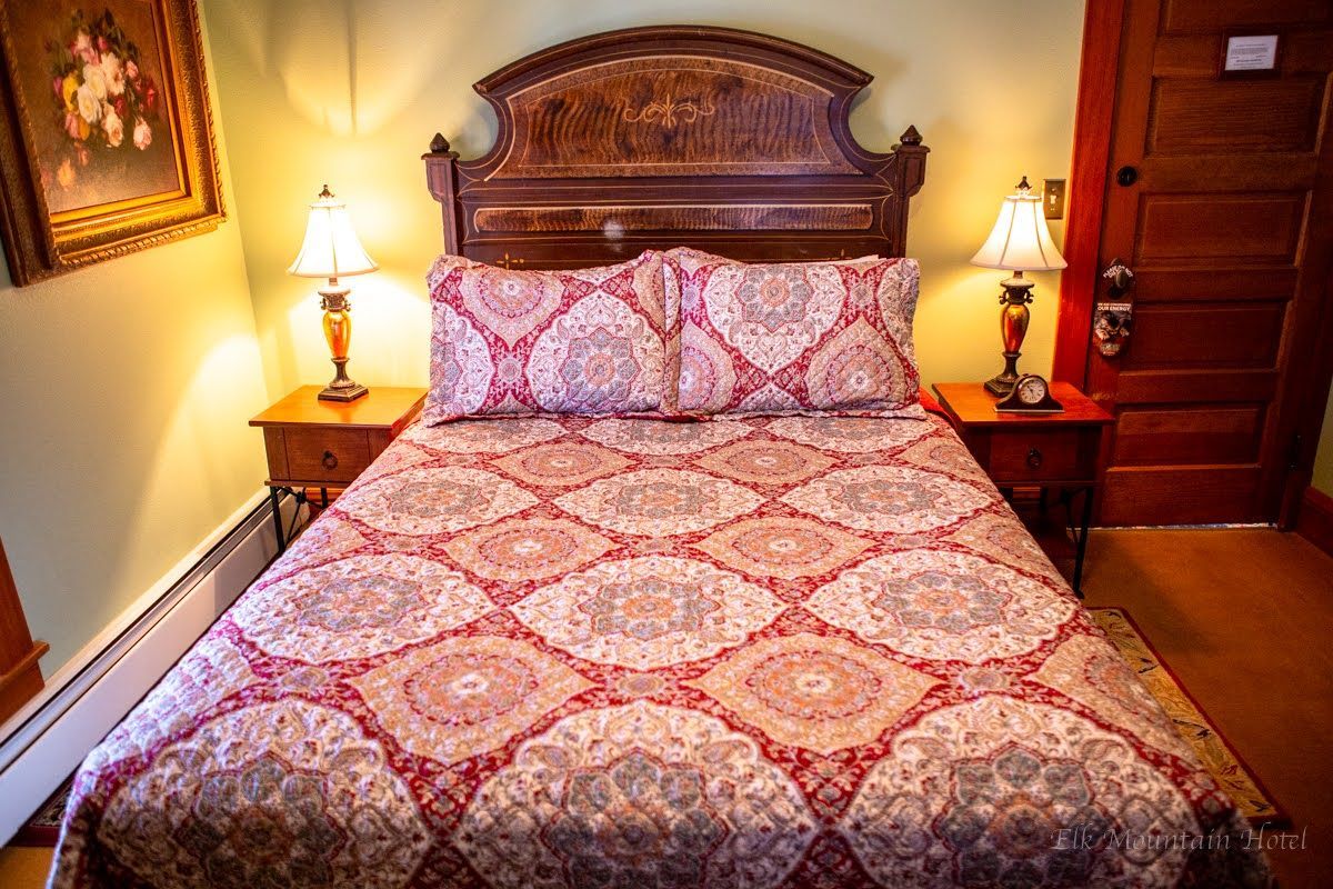 A bedroom with a bed , two lamps , and a door.