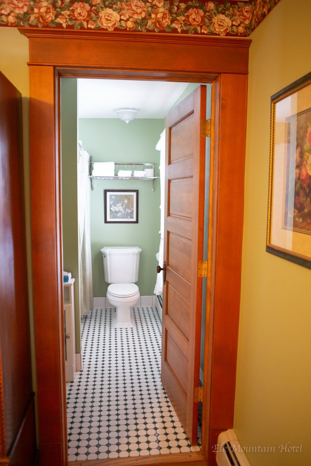 A bathroom with a toilet and a picture on the wall.