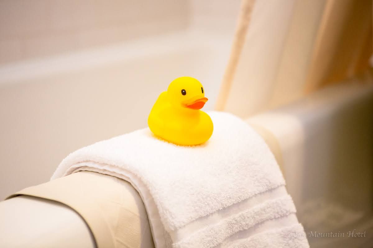 A yellow rubber duck is sitting on a white towel