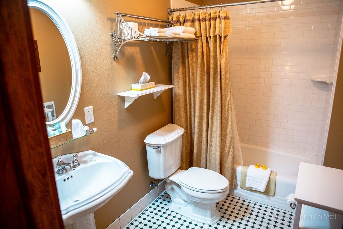 A bathroom with a toilet , sink , mirror and shower curtain.