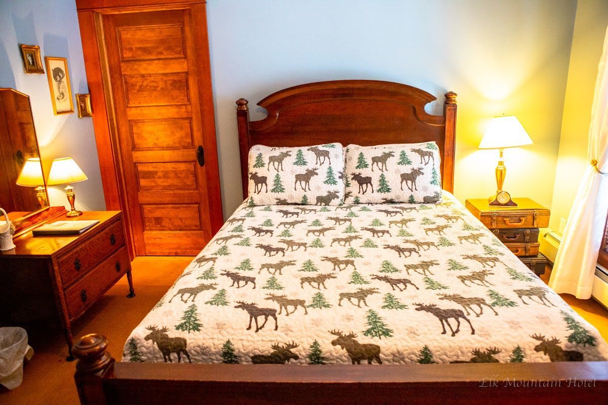 A bedroom with a bed , nightstand , dresser and two lamps.