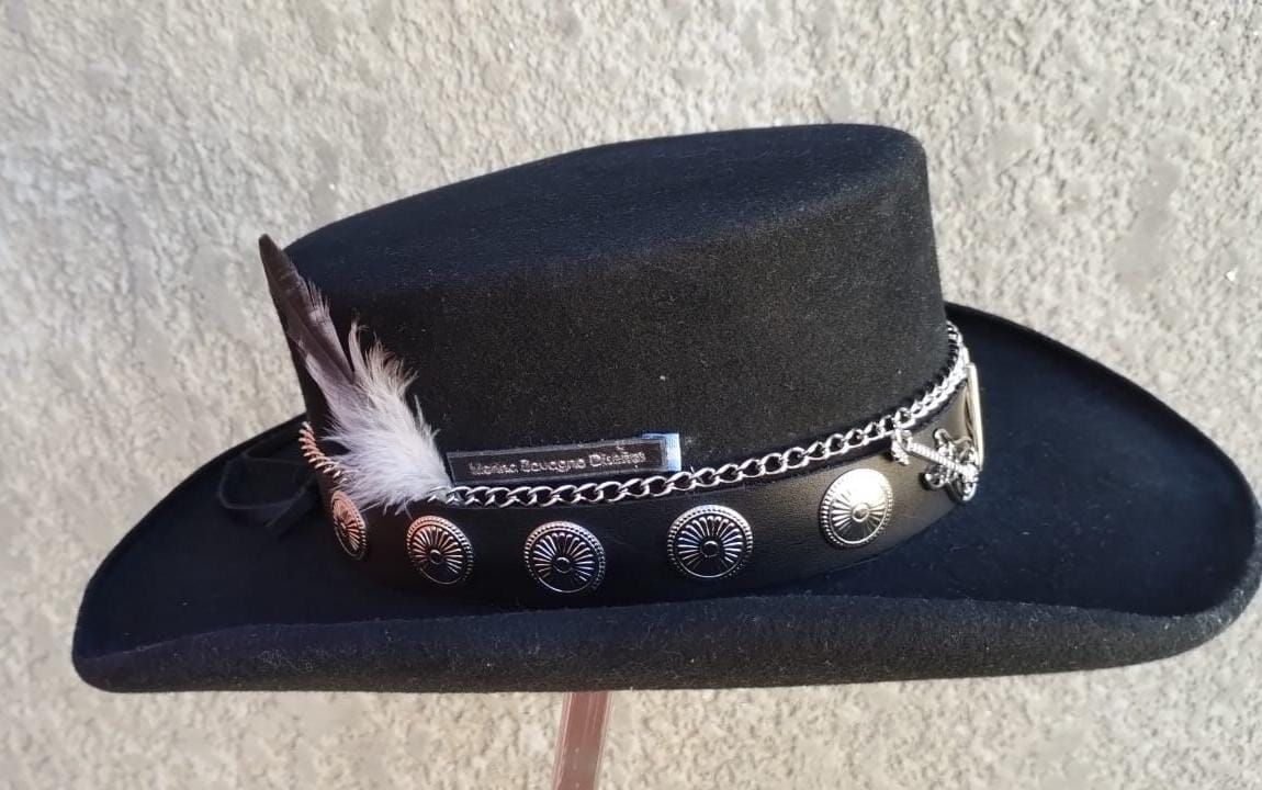 Sombrero negro de ala ancha, banda decorativa con medallones plateados y pluma.