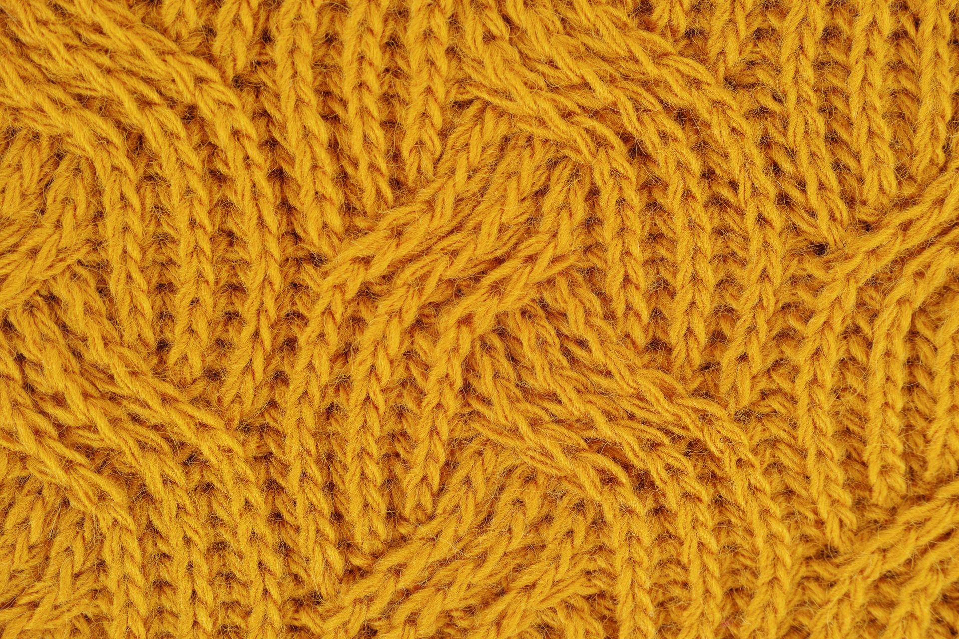 Primer plano de un tejido de punto amarillo mostaza con un patrón de trenzas.