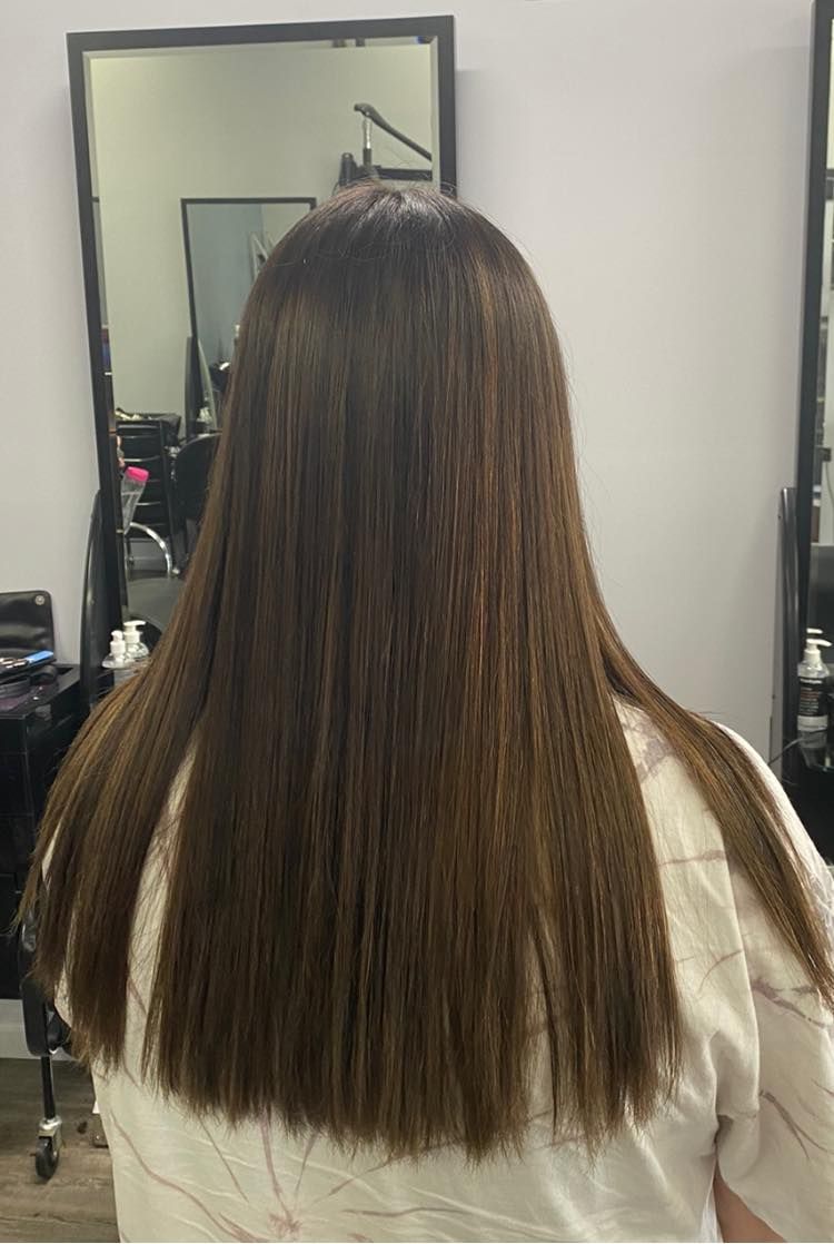 A Woman With Long Hair Is Sitting In Front Of A Mirror In A Salon — Klic's Hair Design In Earlville, QLD