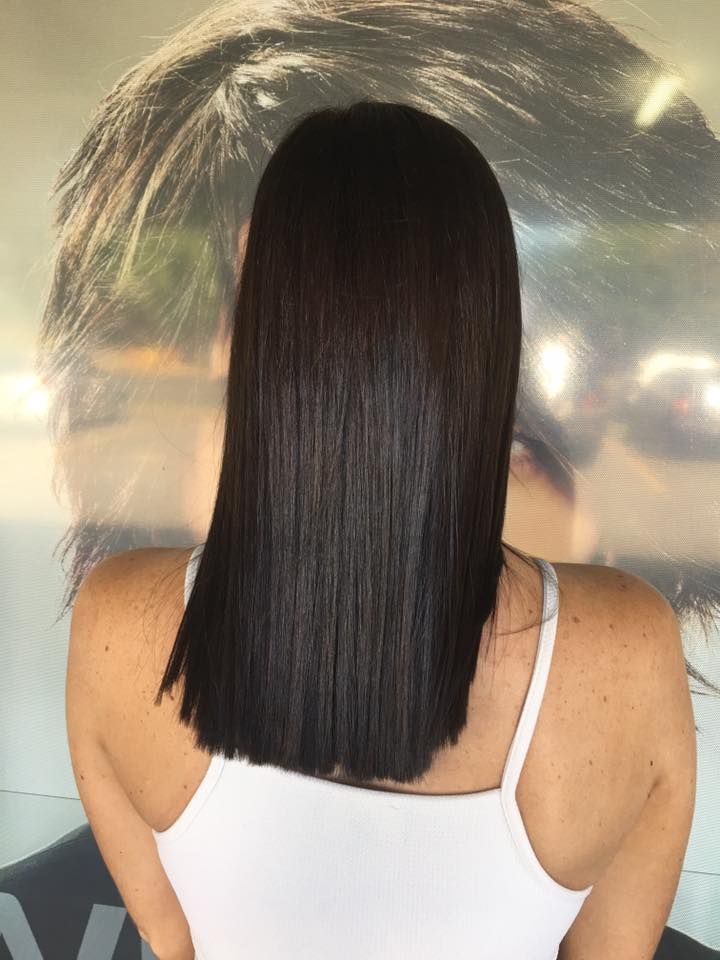 A Woman With Long Black Hair Is Wearing A White Tank Top — Klic's Hair Design In Earlville, QLD