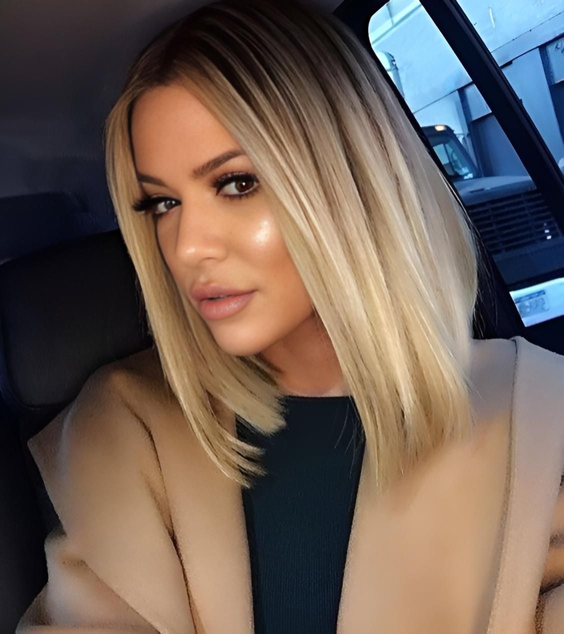 A Woman With Blonde Hair Is Sitting In A Car Wearing A Tan Coat — Klic's Hair Design In Earlville, QLD