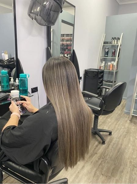 A Woman Is Sitting In A Chair In A Hair Salon— Klic's Hair Design In Earlville, QLD