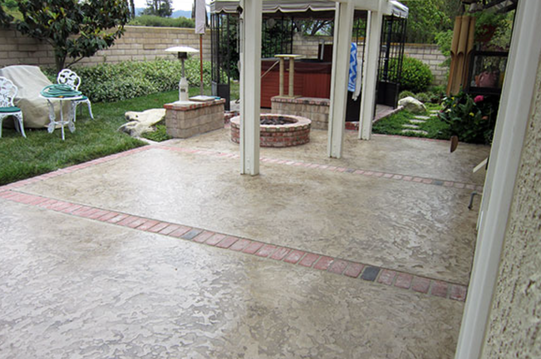 Patio with concrete floor, brick borders, fire pit, and covered seating area.