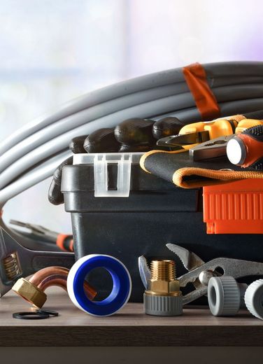 A toolbox filled with tools and a hose on a table.