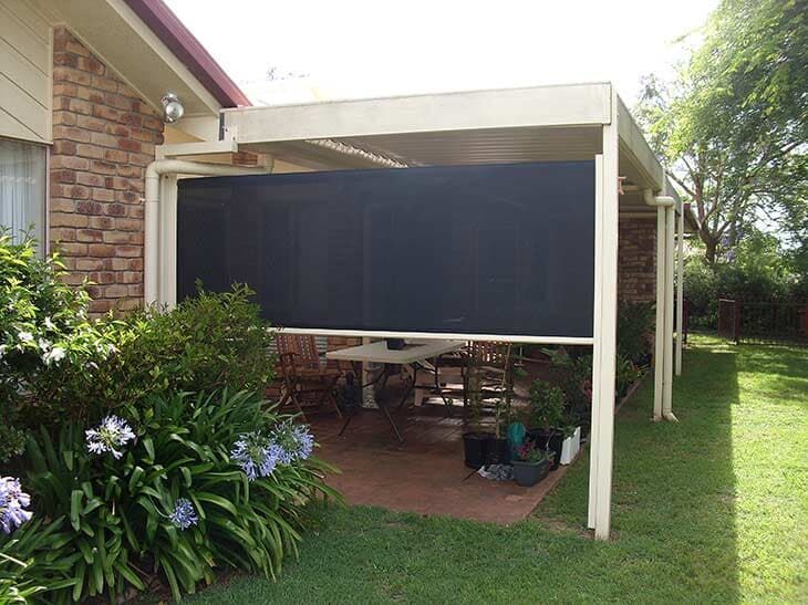Patio With Retractable Black Screen. Brick Building, Green Lawn — Toowoomba Shade & Canvas in Harristown, QLD