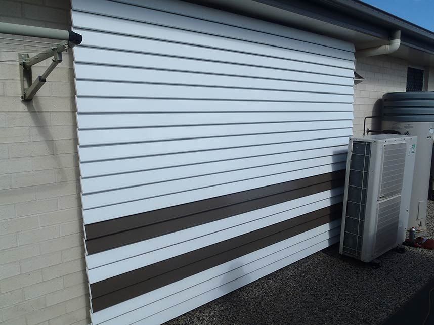 White and Brown Siding on a Building Exterior With an Air Conditioning Unit — Toowoomba Shade & Canvas in Gatton, QLD