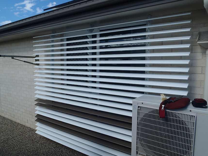 White Louvered Shutters Covering a Window on a Brick Building — Toowoomba Shade & Canvas in Highfields, QLD