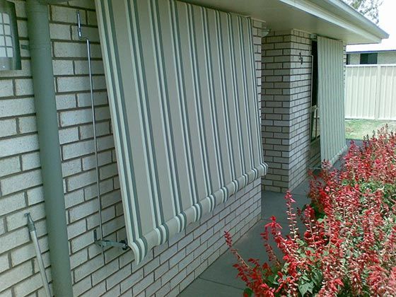 A Cream and Green Striped Awning Hangs Over a Brick Wall — Toowoomba Shade & Canvas in Harristown, QLD