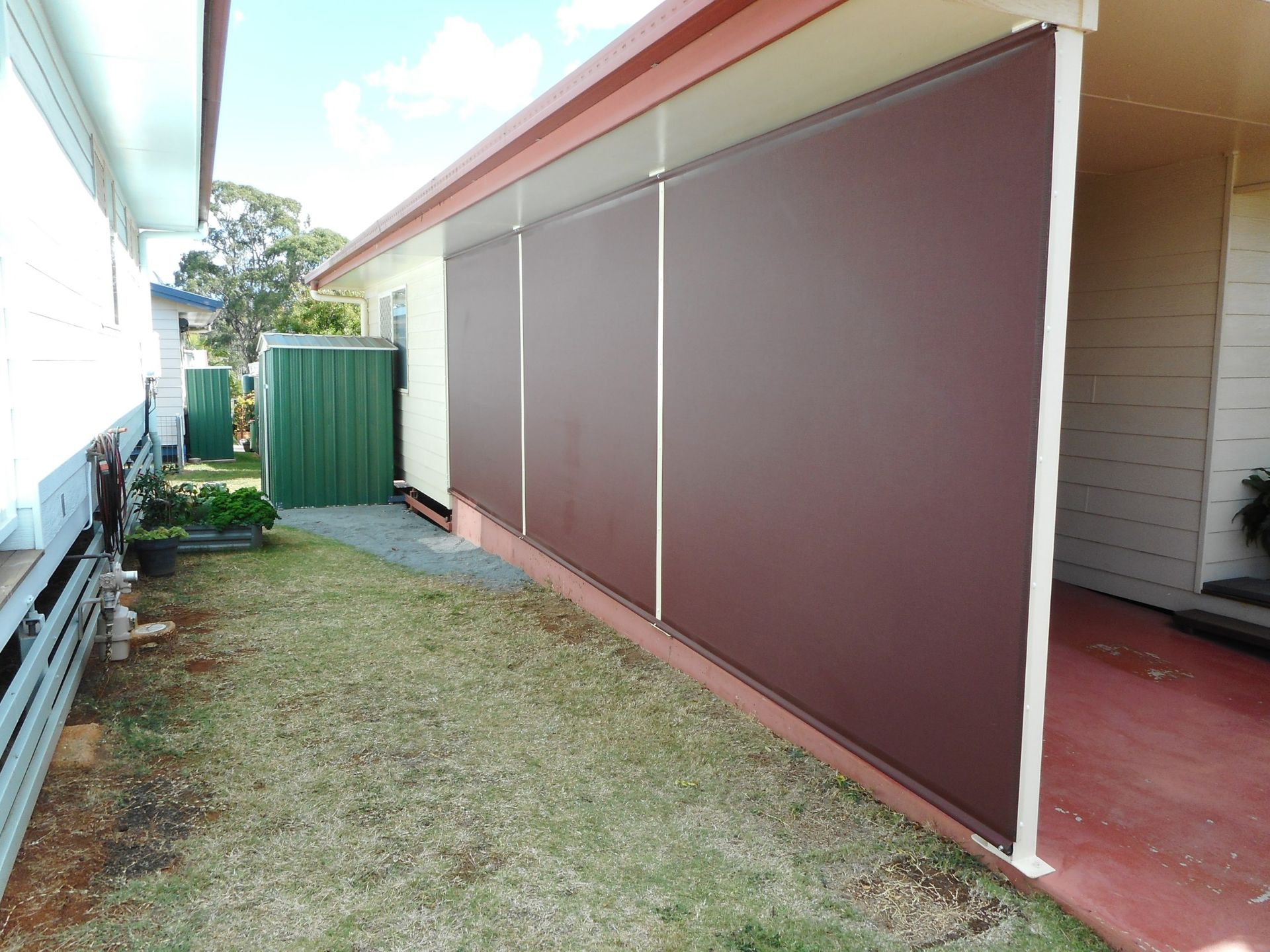 Brown Outdoor Blinds Covering a Side Patio, Beside a Grassy Yard — Toowoomba Shade & Canvas in Harristown, QLD