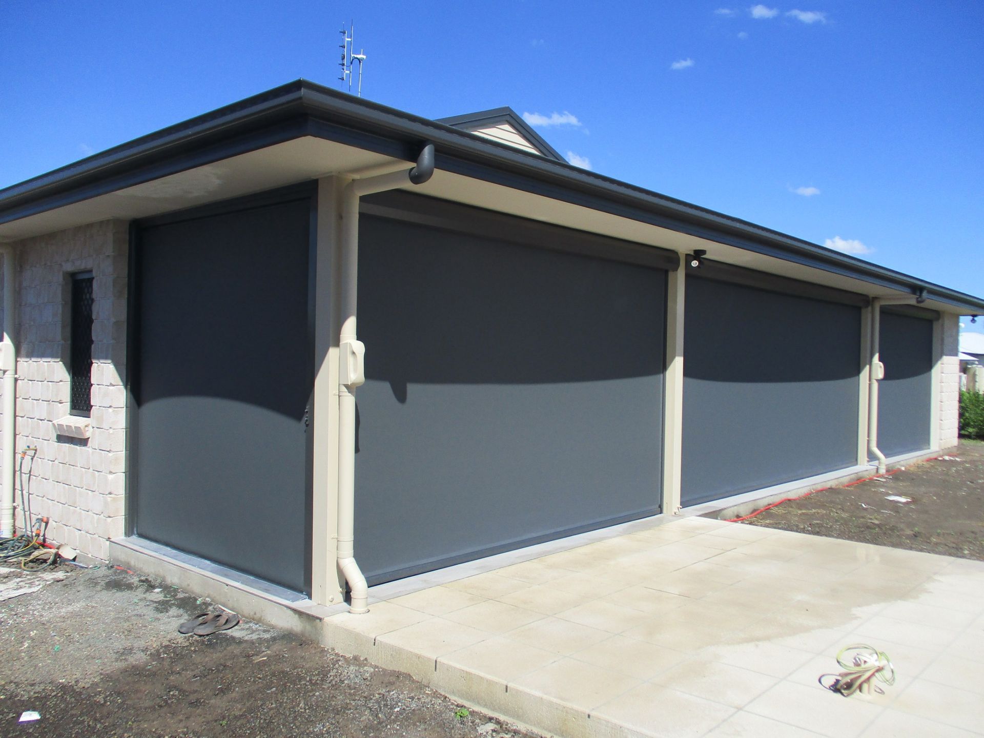 Dark Grey Outdoor Roller Shades on a Beige Brick Building — Toowoomba Shade & Canvas in Harristown, QLD