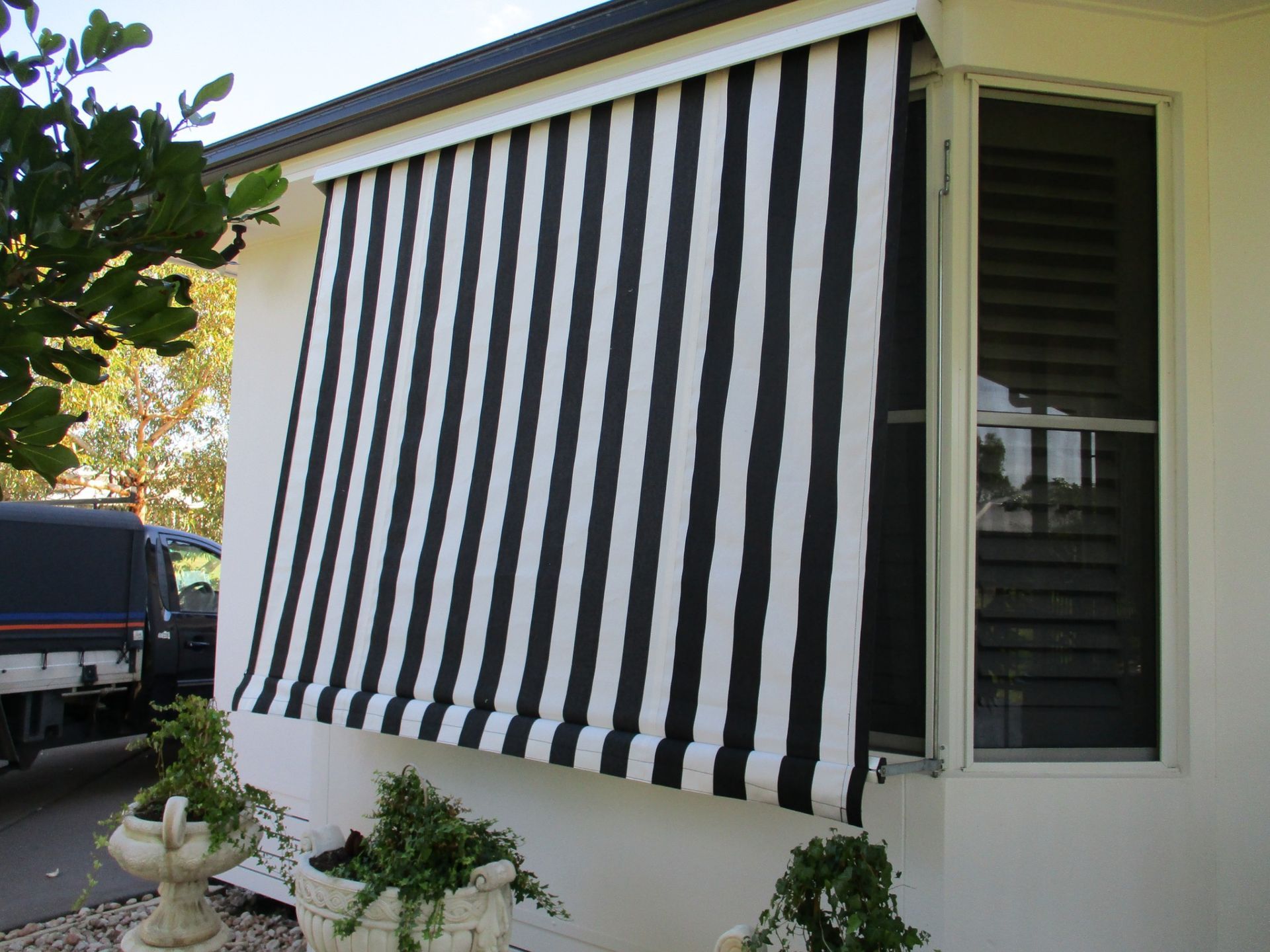 Black and White Striped Awning Over a Window on a White House — Toowoomba Shade & Canvas in Harristown, QLD
