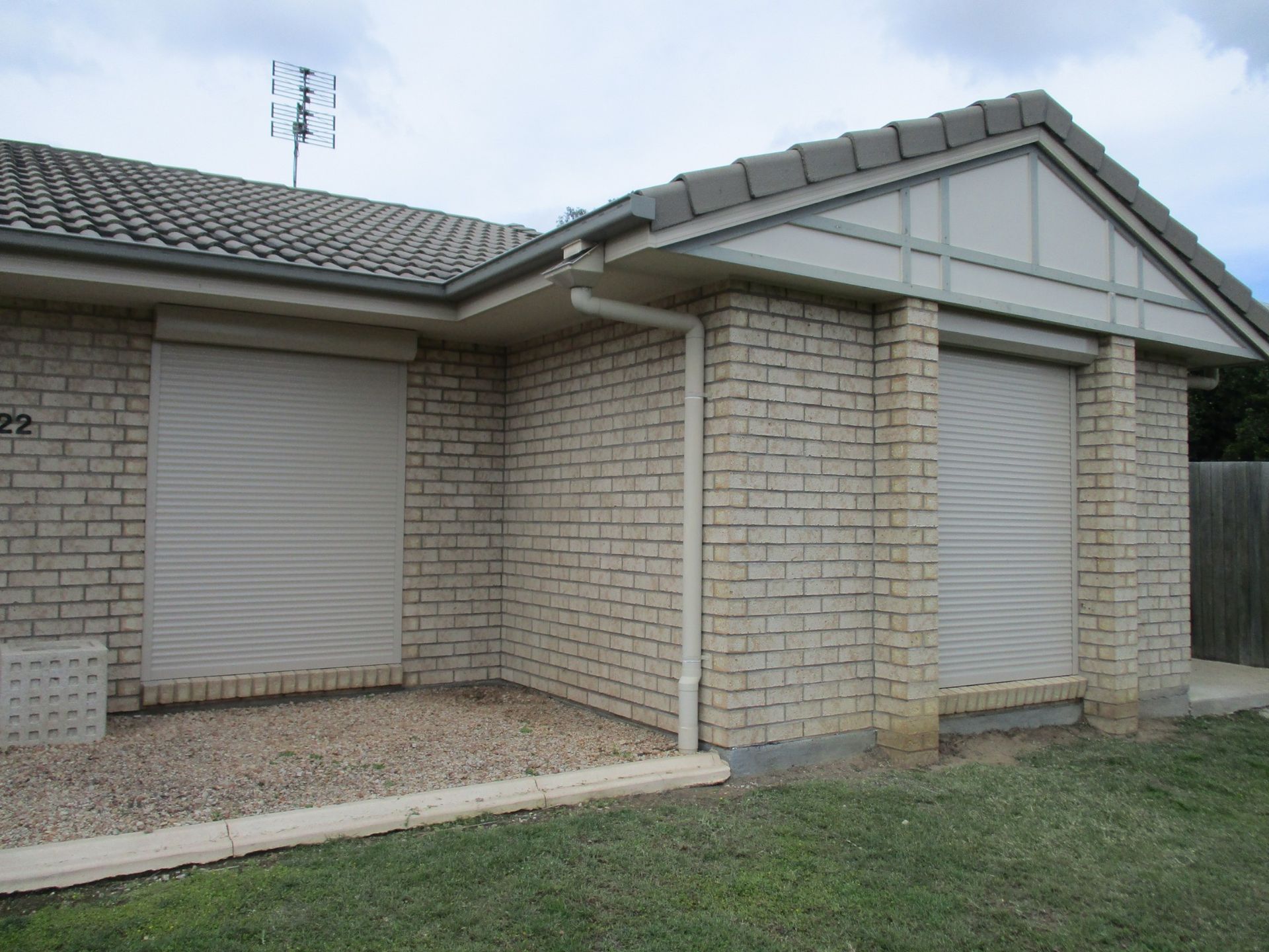 Beige Brick House With Closed Roller Shutters, Roof, and Antenna — Toowoomba Shade & Canvas in Warwick, QLD