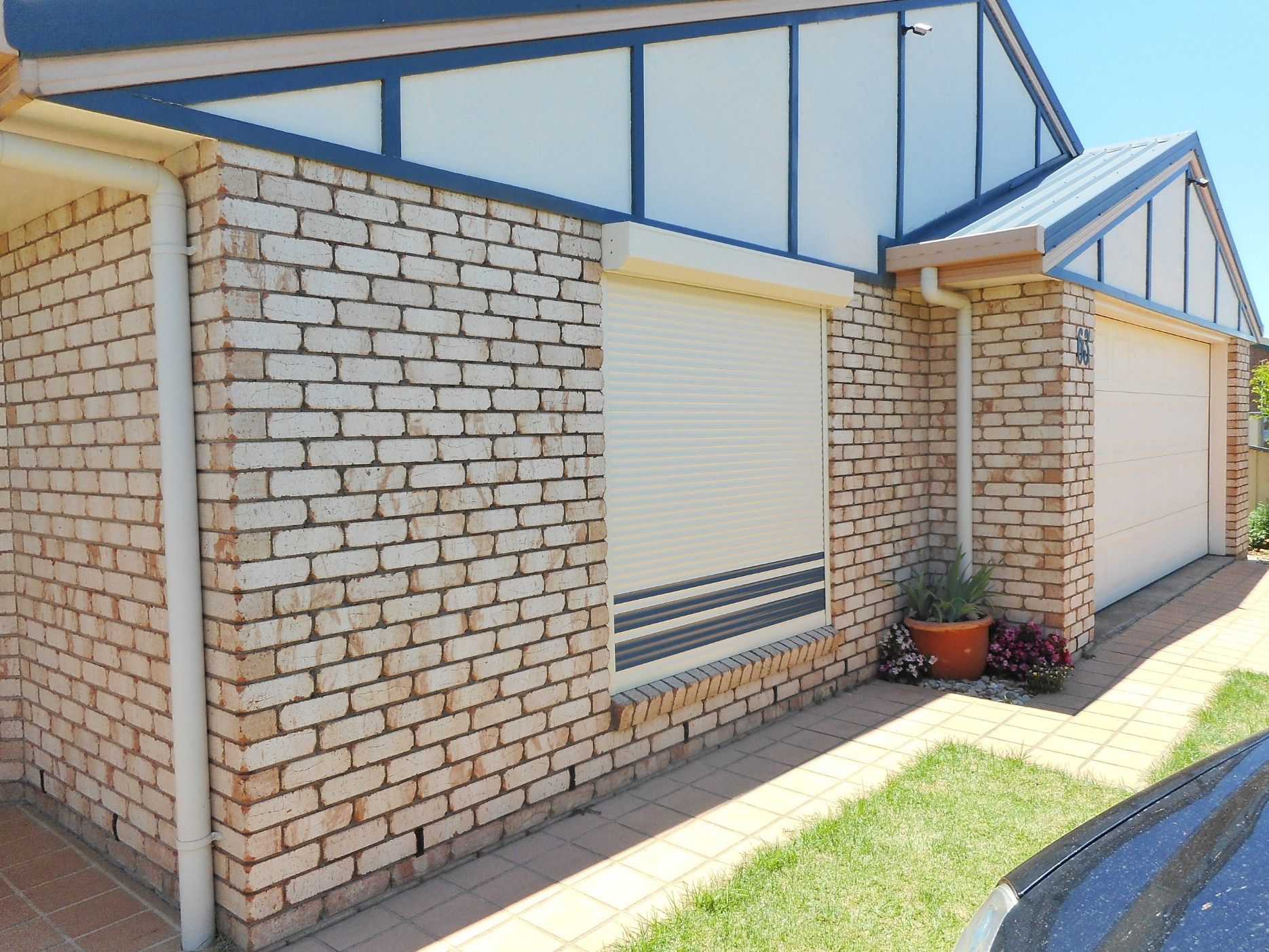 Brick House With a Closed Cream-colored Roller Shutter — Toowoomba Shade & Canvas in Harristown, QLD