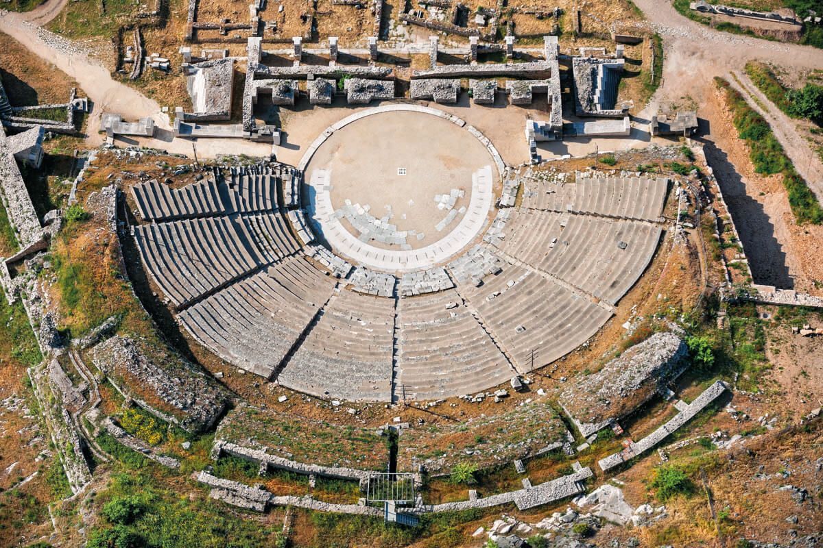 Αεροφωτογραφία του αρχαίου πέτρινου θεάτρου στη Νικόπολη, στην Ελλάδα, που δείχνει την ημικυκλική περιοχή καθισμάτων και τα ερείπια της σκηνής.