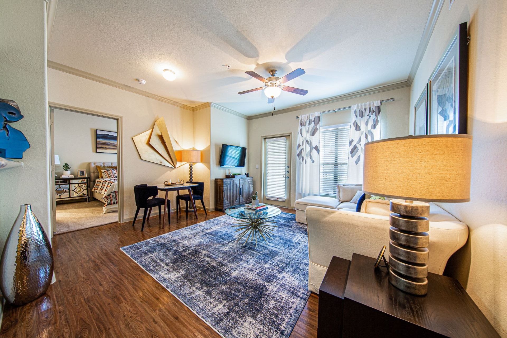 A living room with a couch, table, chairs, and a ceiling fan at Marquis Grand Lakes in Richmond, TX.