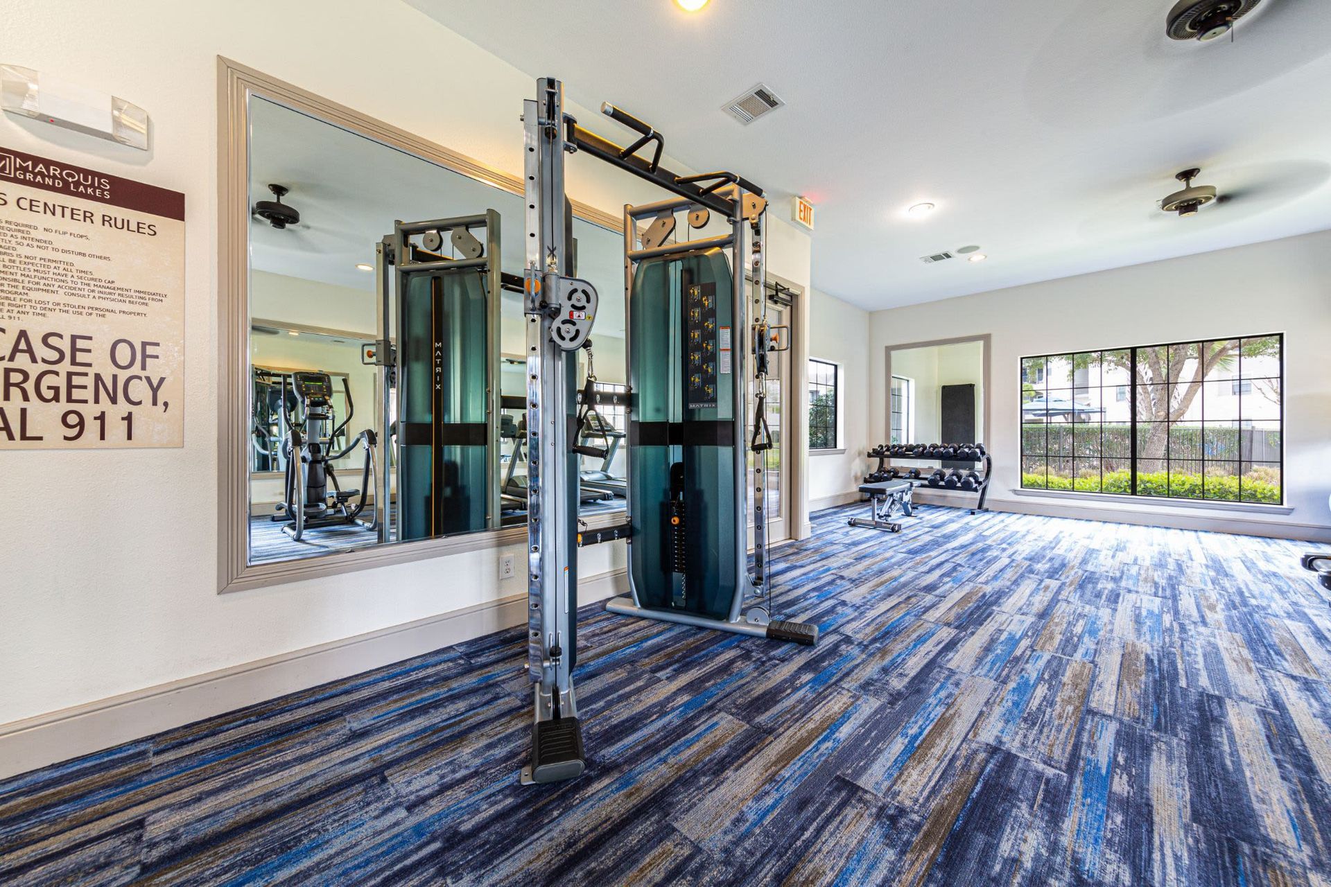 A gym with a lot of equipment and a large mirror at Marquis Grand Lakes in Richmond, TX.
