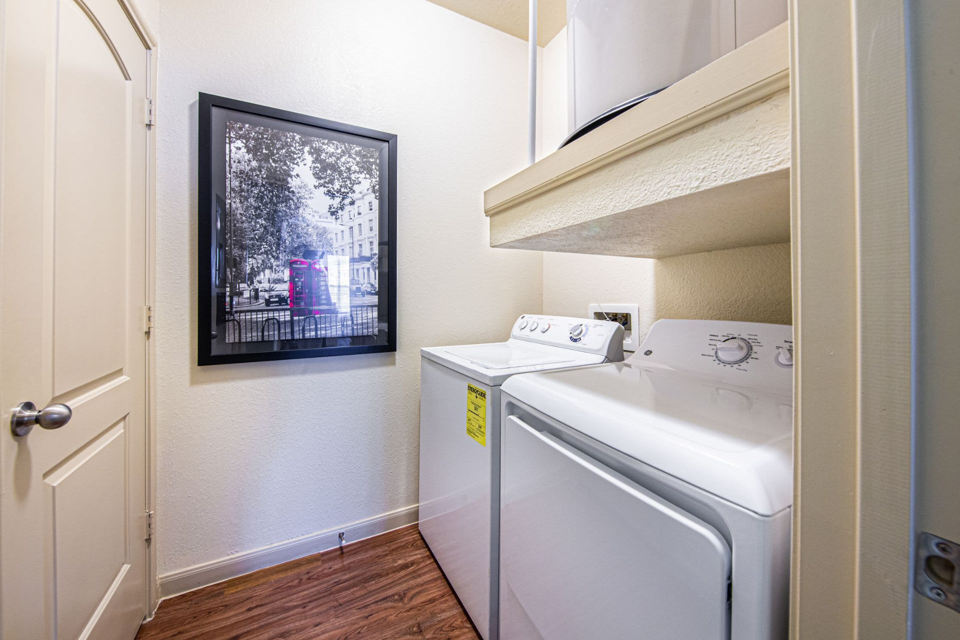 A laundry room with a washer and dryer and a picture on the wall at Marquis Grand Lakes in Richmond, TX.