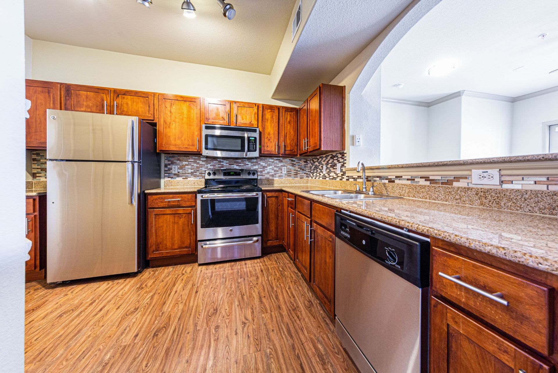 A kitchen with stainless steel appliances and wooden cabinets at Marquis Grand Lakes in Richmond, TX.