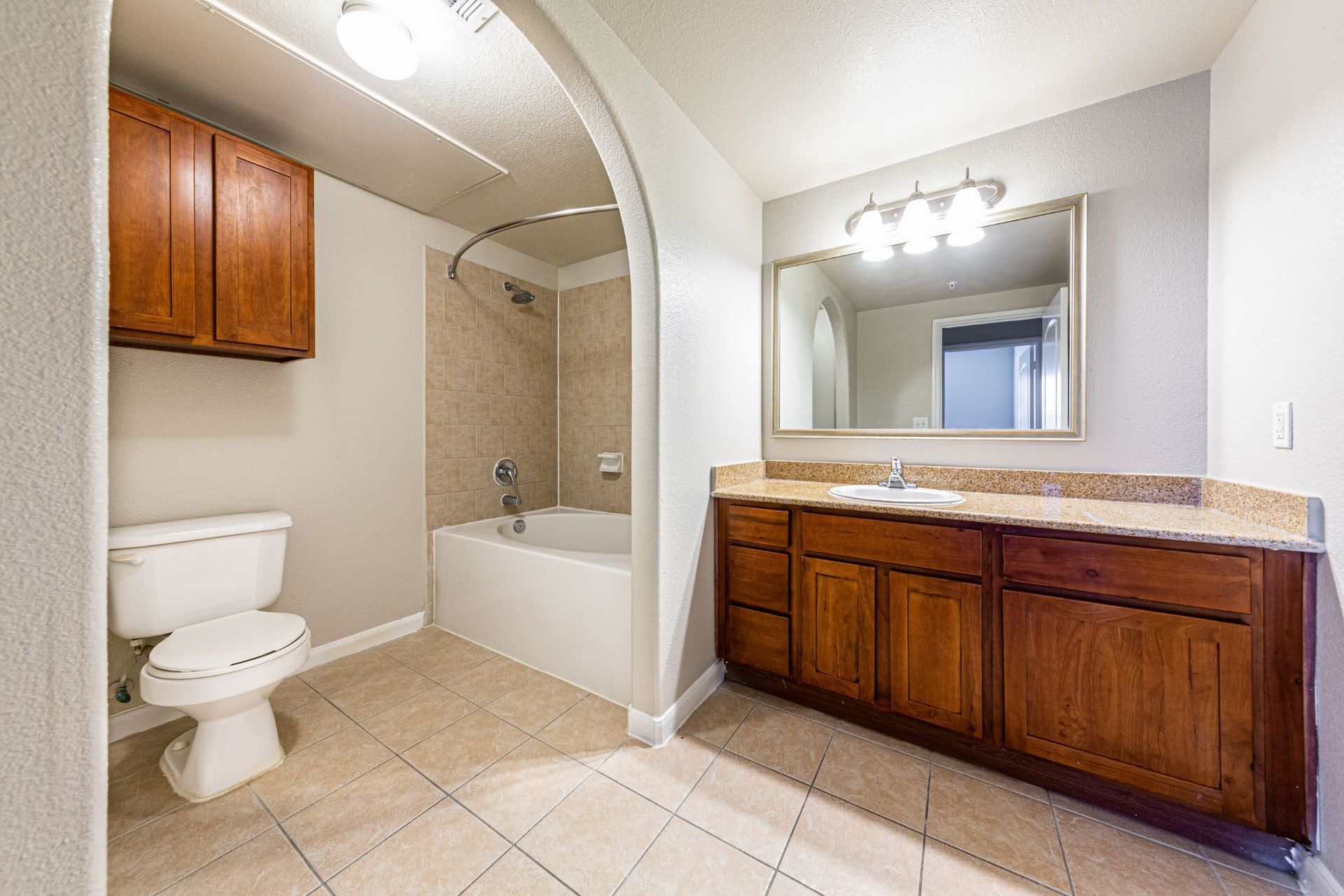A bathroom with a toilet, sink, bathtub and mirror at Marquis Grand Lakes in Richmond, TX.
