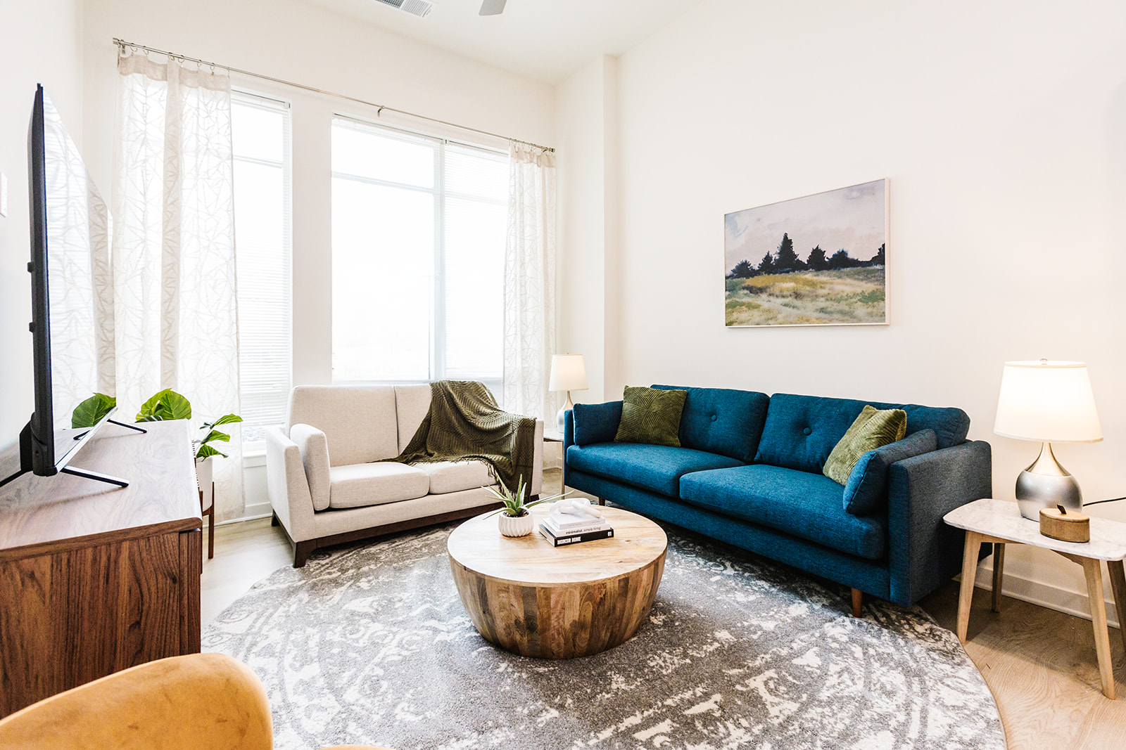 Bright living room with blue sofa and large windows at Opal Largo Station Apartments in Largo, MD.