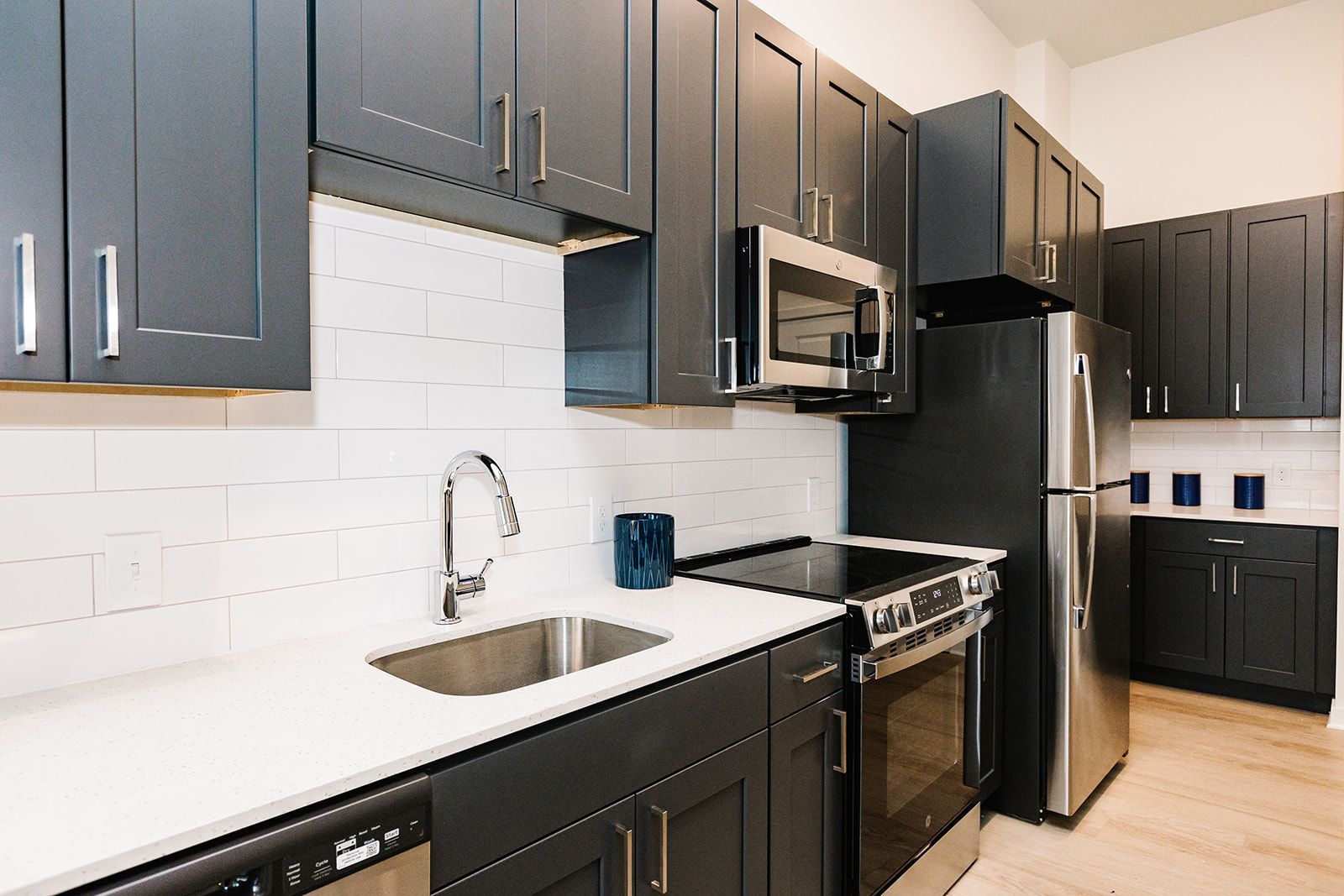 Apartment kitchen with dark cabinets, white countertops, and stainless steel appliances at Opal Largo Station Apartments in Largo, MD.