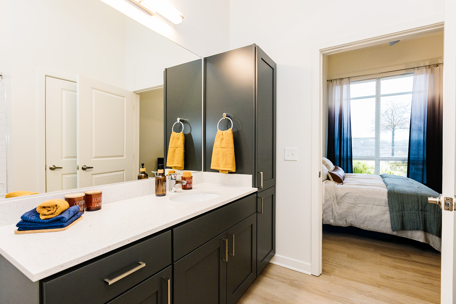 Modern bathroom vanity with double sinks and a view into a bright bedroom through an open doorway at Opal Largo Station Apartments in Largo, MD