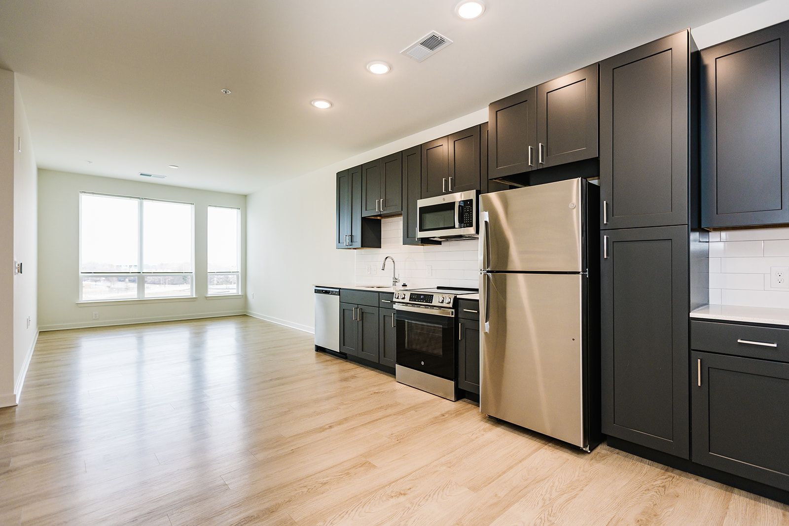 Open-concept kitchen and living area with large windows at Opal Largo Station Apartments in Largo, MD.