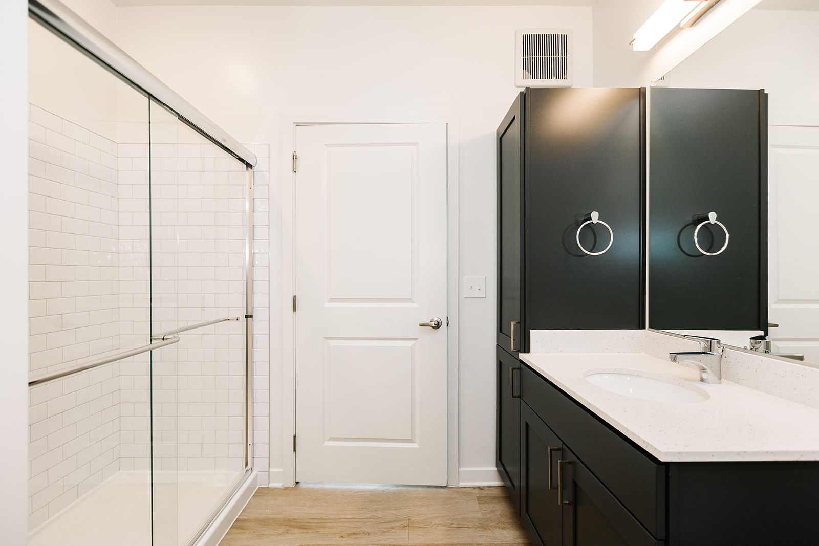Modern bathroom with double vanity, dark cabinets, white walls, and a glass shower enclosure at Opal Largo Station Apartments in Largo, MD