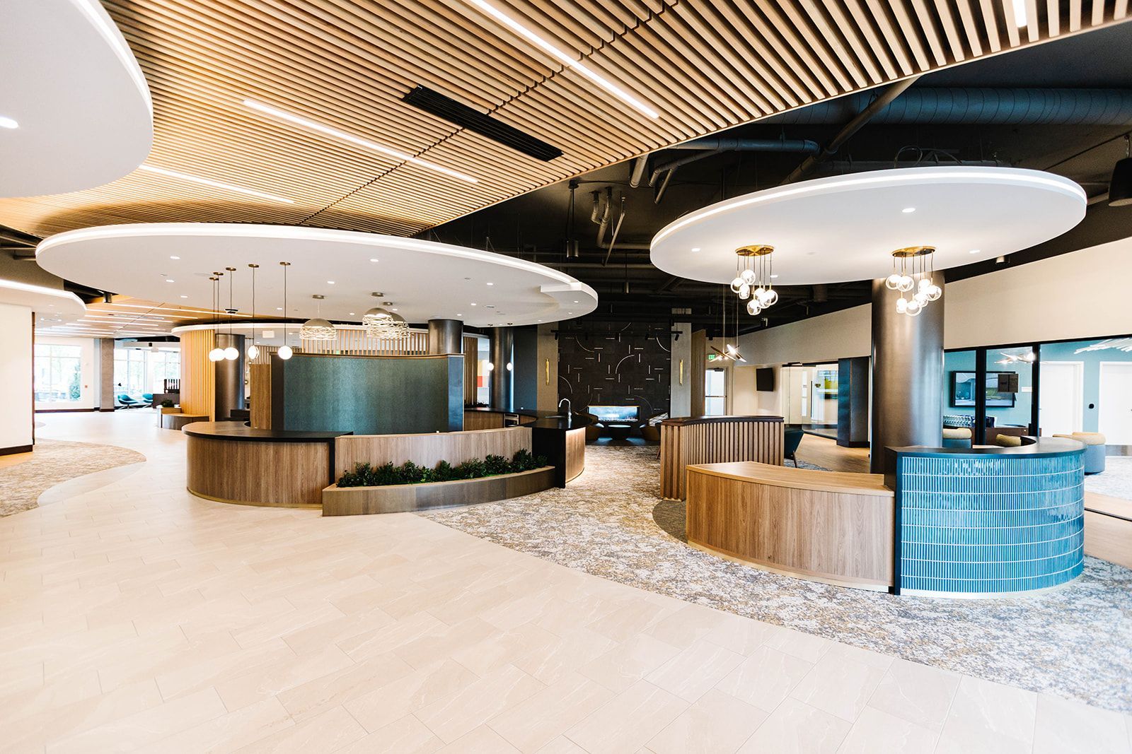 Modern hotel lobby with curved wood ceiling, circular counters, and a bright blue reception desk at Opal Largo Station Apartments in Largo, MD