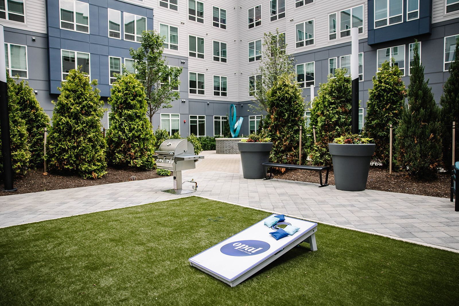 Outdoor courtyard with cornhole game at Opal Largo Station Apartments in Largo, MD.