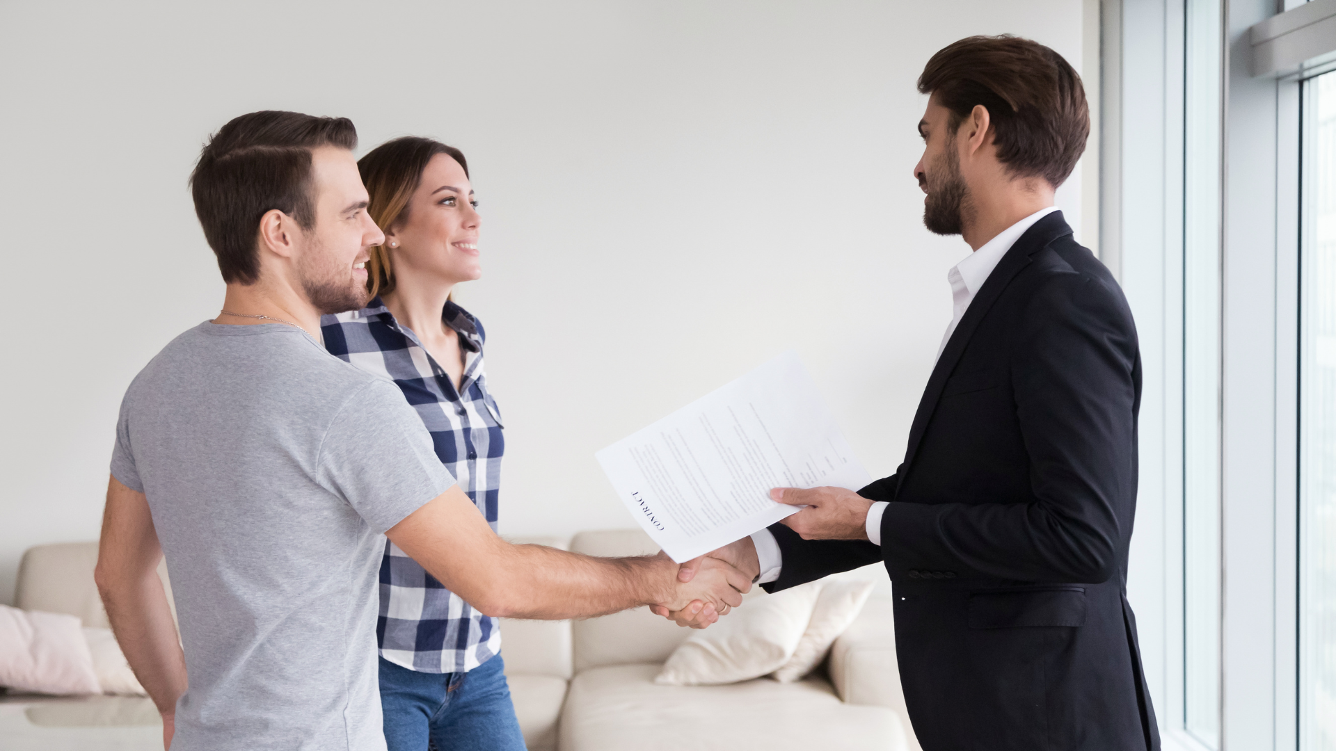 Three people in a living room discussing documents with a suited man during a meeting