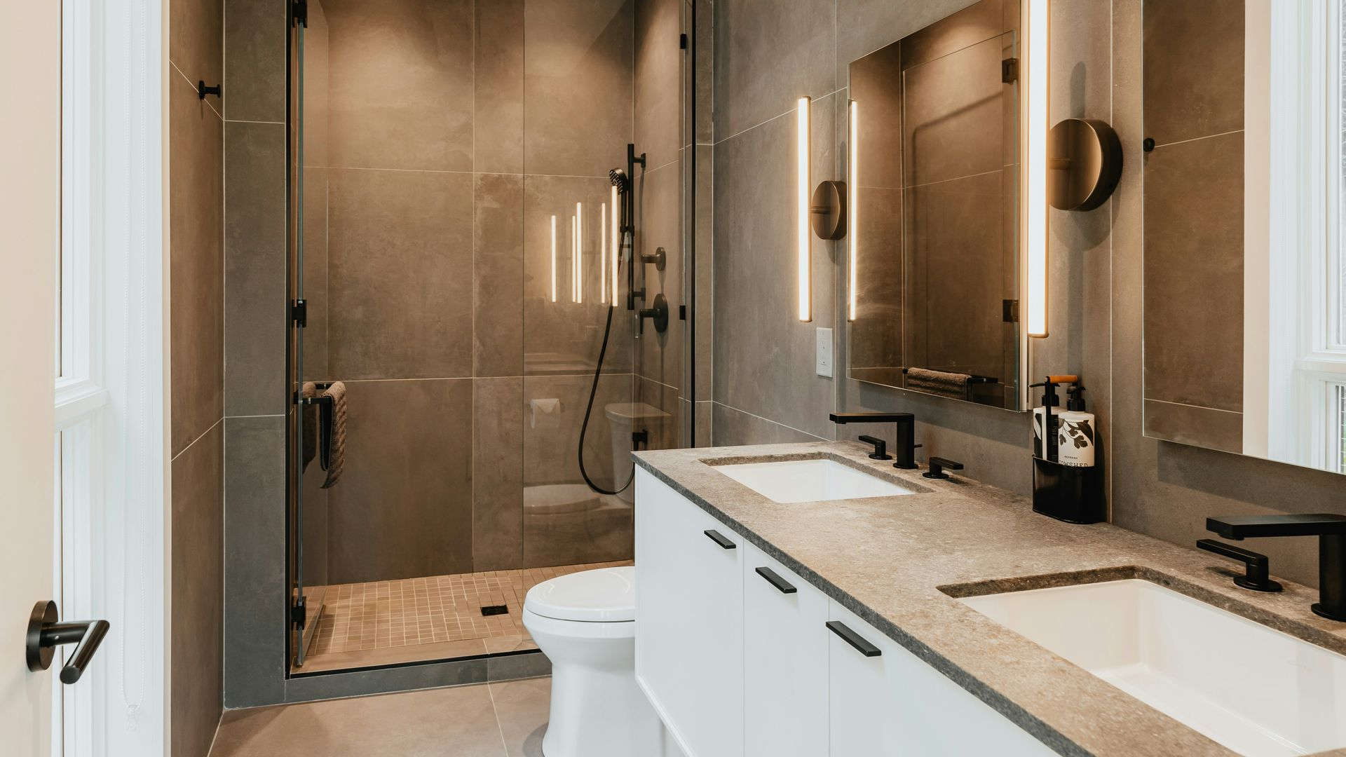 Modern bathroom with double vanity, mirrors, walk-in shower, and neutral tile finishes