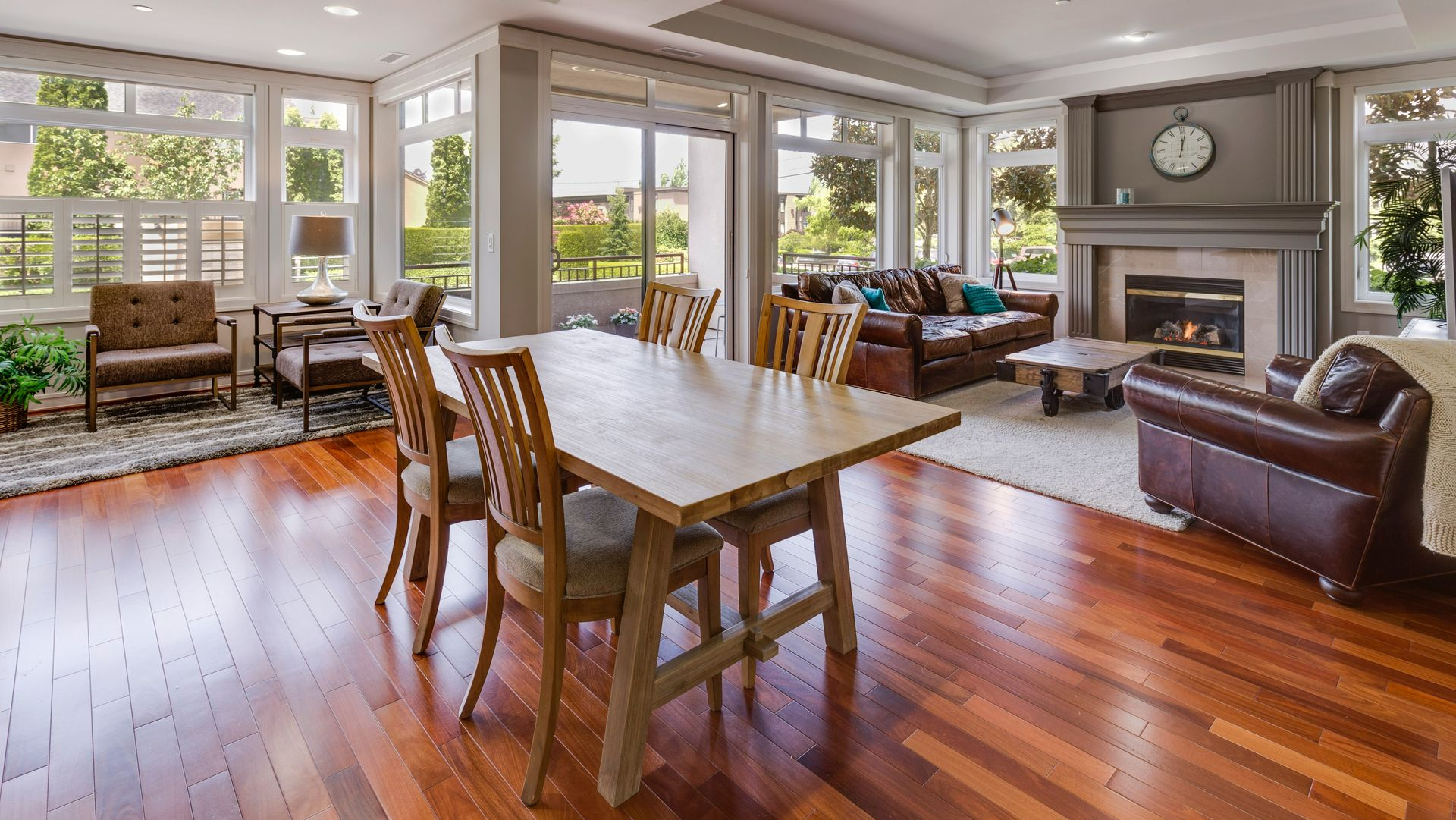 Spacious open-plan living and dining room with hardwood floors, a wooden dining table, fireplace, and leather furniture.