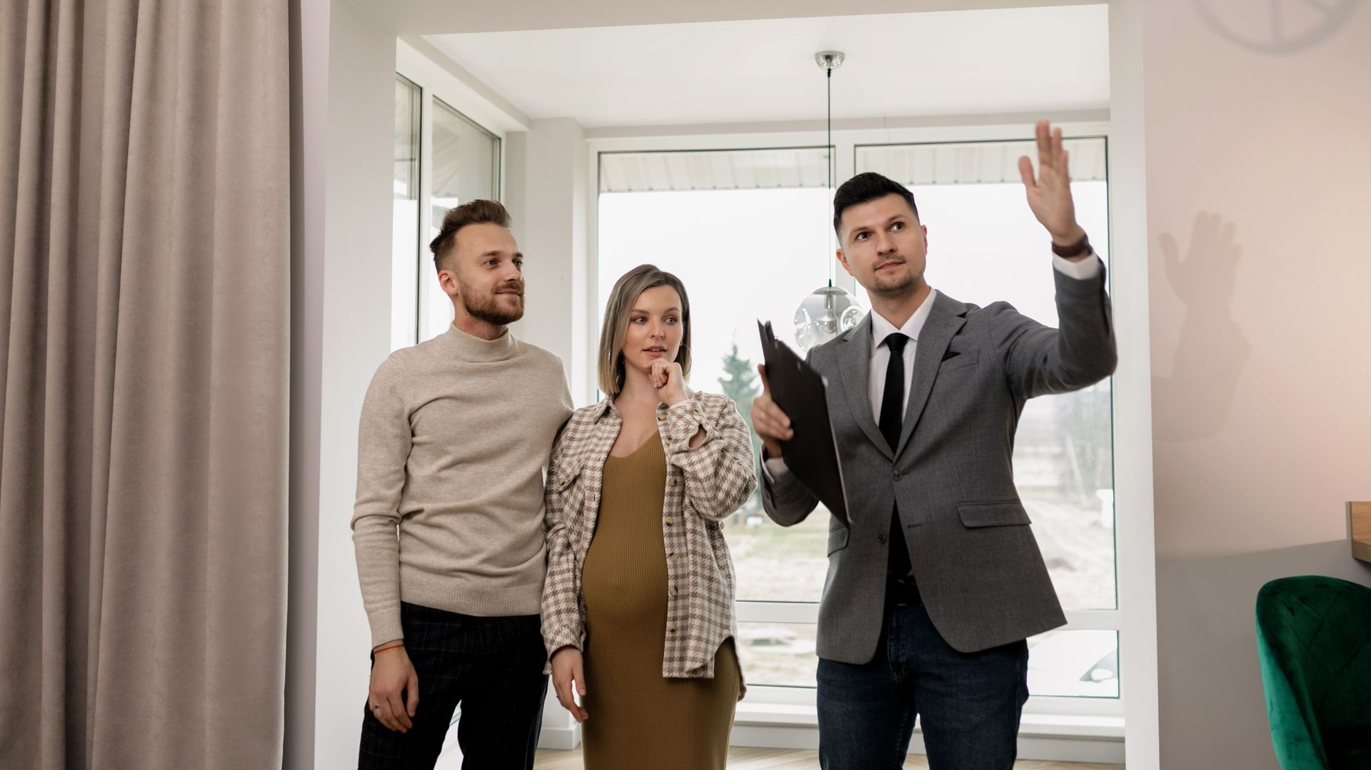 Three people in a living room, one gesturing toward the ceiling as they talk.