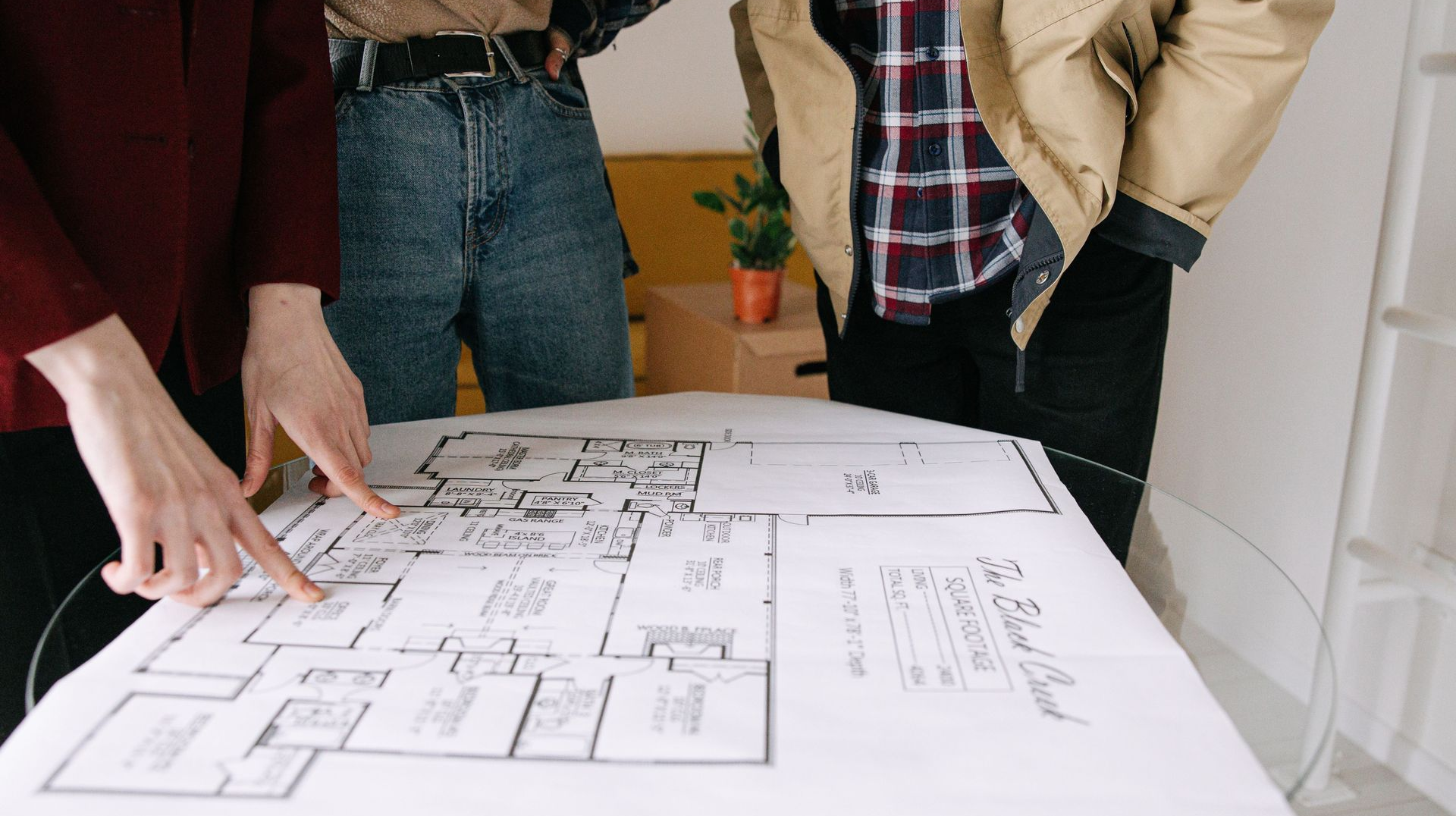 People reviewing a house floor plan on a large table.