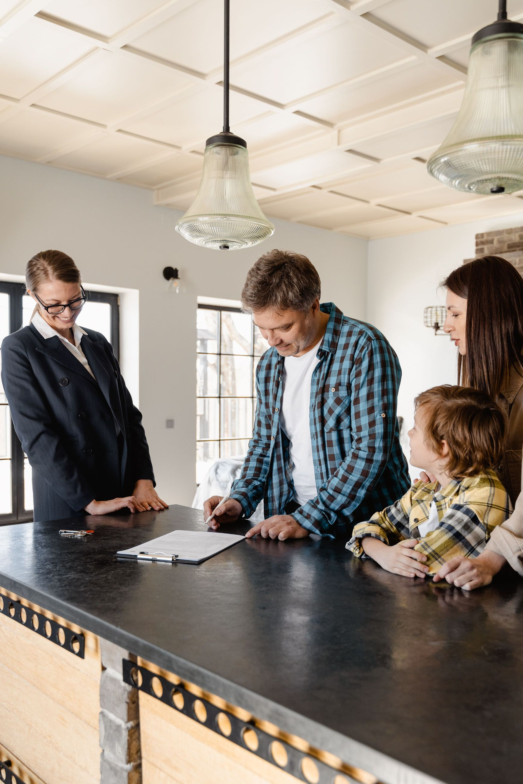 People reviewing paperwork at a kitchen island under pendant lights