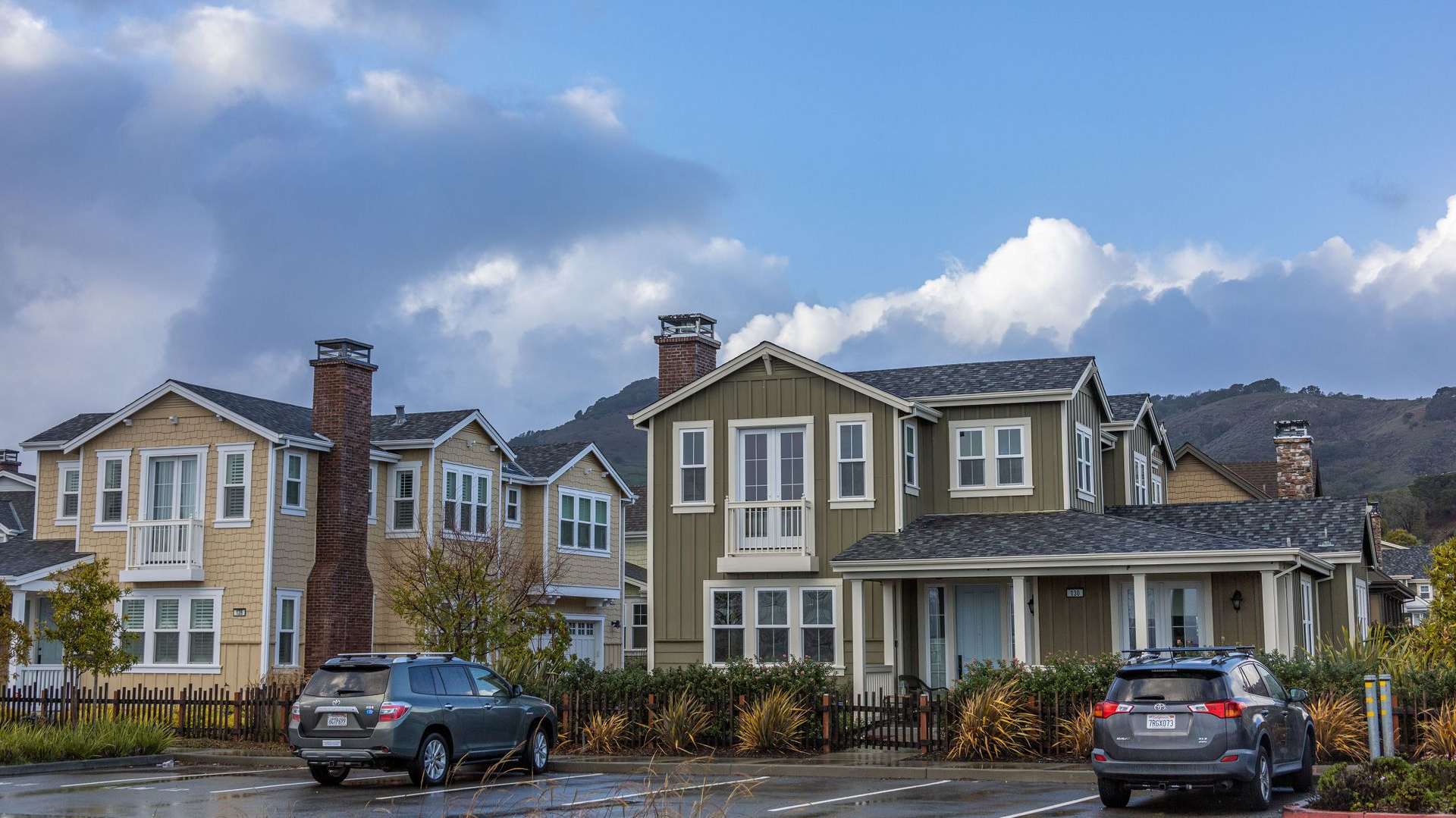 Row of modern townhomes with parked cars and cloudy sky in a residential neighborhood