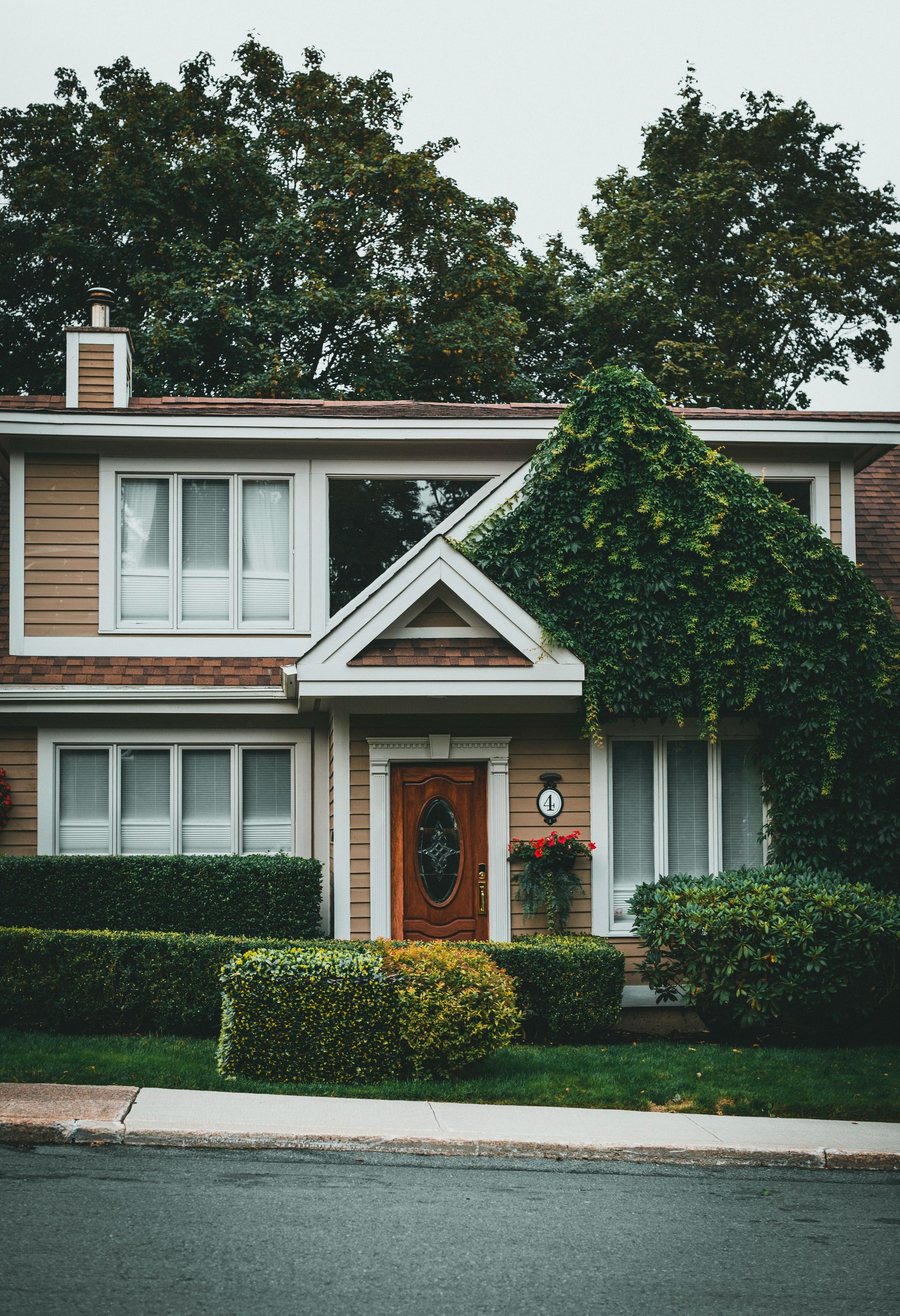 Two-story suburban house with ivy-covered front porch and a white SUV parked in the driveway