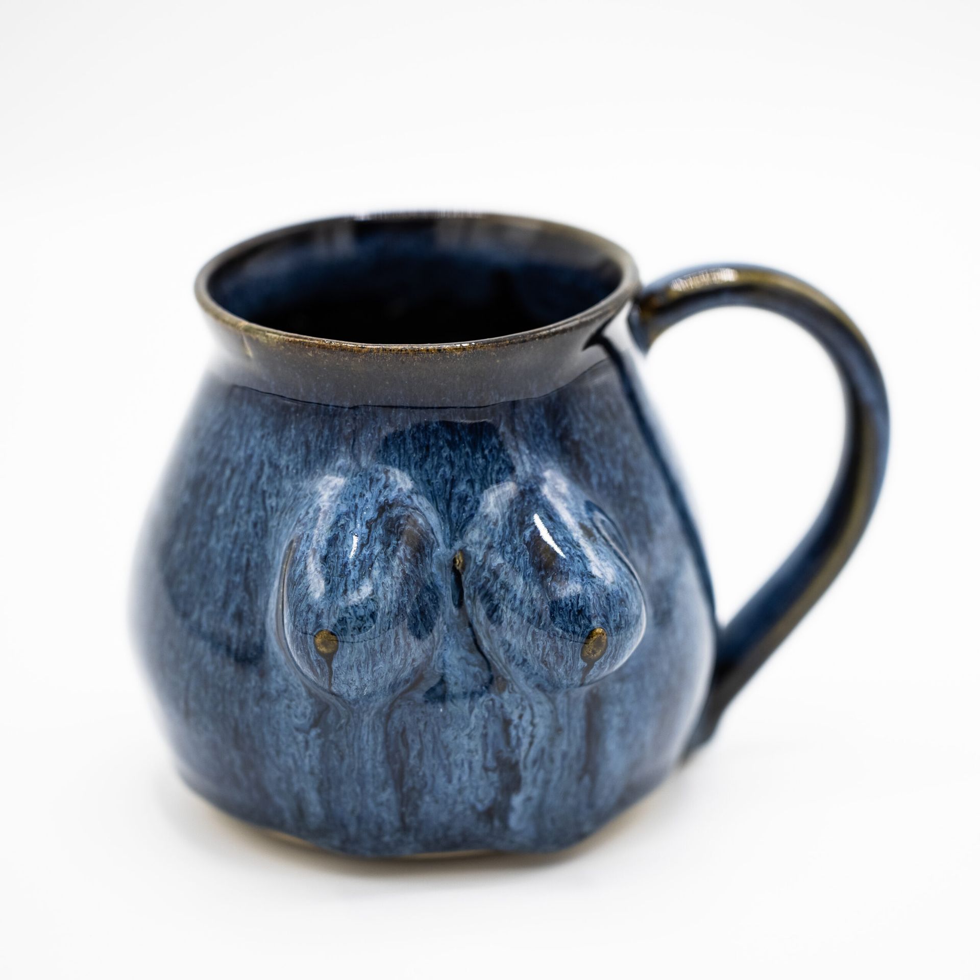 A blue, rounded ceramic mug with two sculpted, breast-like protrusions on its side.