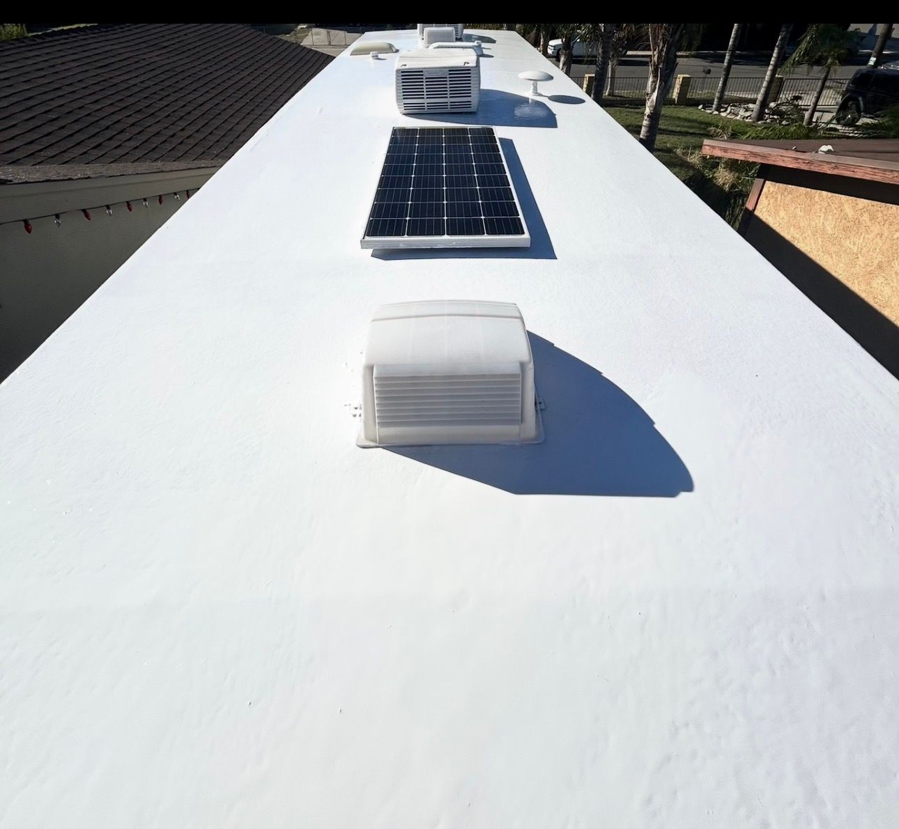 White flat roof with skylights and blue solar panels in bright sunlight