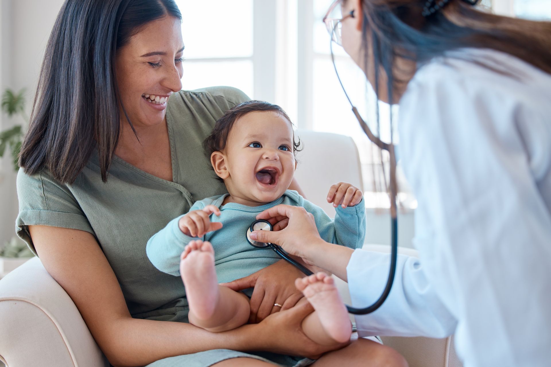 Doctor listening to the heart of a laughing baby with a stethoscope