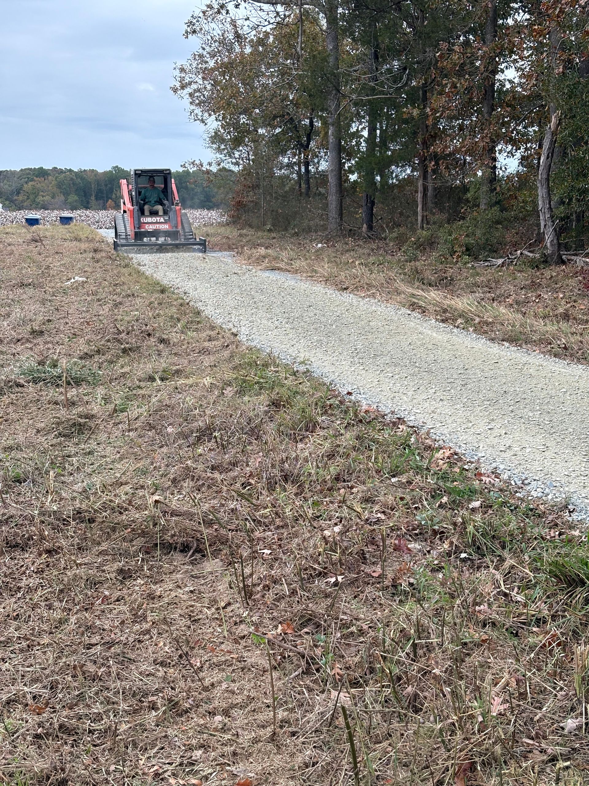 A bulldozer is driving down a dirt road in a field.