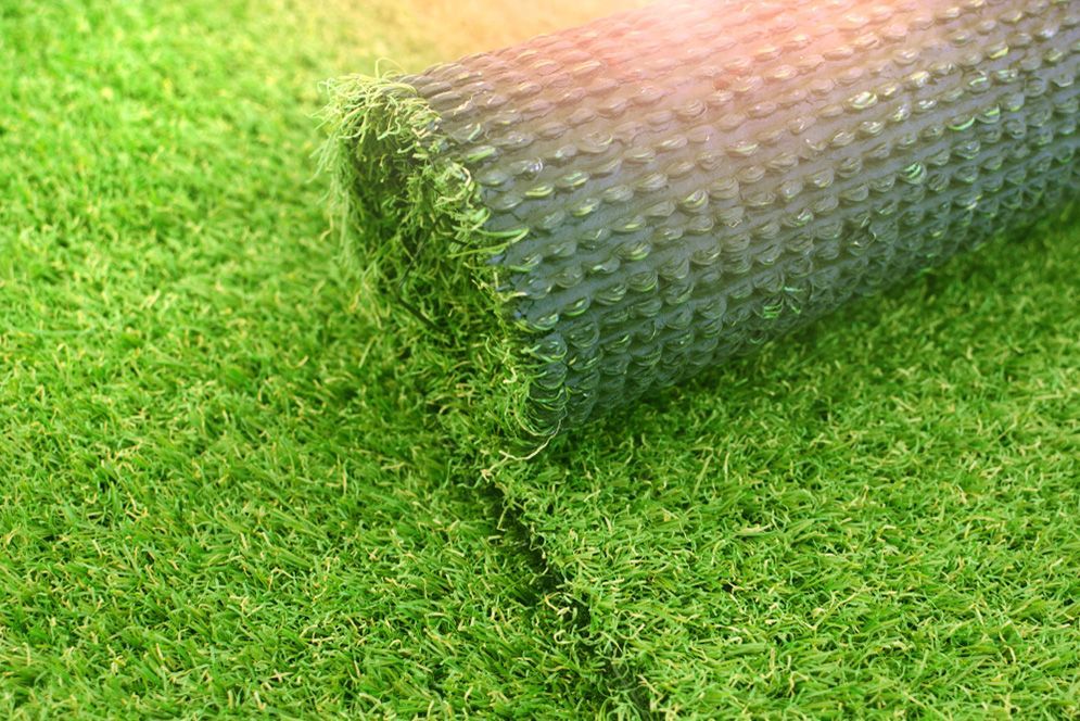 A Roll of Artificial Grass is Sitting on Top of a Lush Green Field — Highfields Turf in Miles, QLD
